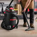 A man using a Shop-Vac wet/dry utility vacuum to clean a floor.