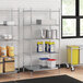A metal Regency wire shelving unit in a kitchen with white and blue plastic containers on the shelves.