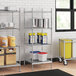 Stainless steel wire shelves with solid bottoms holding white and blue plastic containers with red lids.