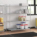 A Regency chrome wire shelving unit in a kitchen with white and red plastic containers on the shelves.