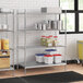 A stainless steel wire shelf unit with white and blue plastic containers on the shelves.