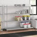 A stainless steel wire shelving unit with four shelves and a solid stainless steel bottom.