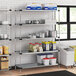 Regency galvanized steel shelves in a school kitchen with food on them.