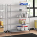 A Regency chrome wire shelving unit in a kitchen with white and blue plastic containers on it.
