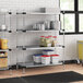 Regency galvanized steel shelves with white and blue containers on them in a professional kitchen.