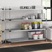 A Regency galvanized steel shelving unit with blue and white plastic bins on the shelves.