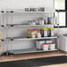 Regency galvanized steel shelves holding food in a professional kitchen.