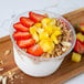 A bowl of Pitaya Foods organic coconut sorbet with strawberries and nuts.