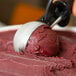 A person scoops Pitaya Foods Organic Acai Sorbet with a metal handle.