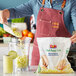 A person pouring Dole Chef-Ready Cuts IQF Diced Apples into a blender.