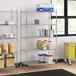 A Regency metal wire shelving unit in a kitchen with white and blue plastic containers on the shelves.