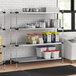 A Regency galvanized steel shelf with food containers on it in a professional kitchen.