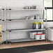 Regency galvanized steel shelving in a school kitchen with white and red containers on the shelves.