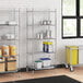 A Regency metal wire shelving unit in a kitchen with containers on the bottom shelf.