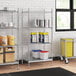 Stainless steel wire shelves with solid stainless steel bottom and white and blue plastic containers with red lids on stainless steel posts.