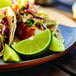 A plate of tacos with lime wedges on the side.