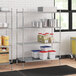 A Regency metal wire shelving unit in a kitchen with white and red plastic containers on the shelves.