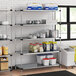 A Regency galvanized steel shelf kit in a professional kitchen with food containers on it.