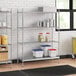 A stainless steel wire shelf unit with solid stainless steel shelves holding containers.