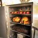A SmokinTex 1400 Pro Series electric smoker with meat and sausages on the rack.