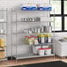 A stainless steel wire shelf kit with 5 shelves filled with containers of food.