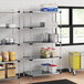 Regency galvanized steel shelves in a school kitchen with food items on them.