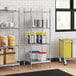Stainless steel wire shelves with food containers on a solid stainless steel shelf.