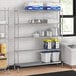 A Regency metal wire shelving unit in a kitchen with white tubs on the bottom shelf.