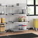 Regency shelving in a professional kitchen with white and blue plastic containers on it.