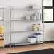 A Regency chrome wire shelving unit in a professional kitchen with metal containers on the shelves.