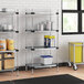 Regency galvanized steel shelves in a professional kitchen with food containers on them.