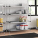 A Regency metal shelving unit in a professional kitchen with food items on it.