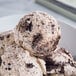 A bowl of Tillamook Cookies and Cream ice cream with a scoop of white ice cream with brown cookie pieces.