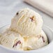 A close up of a bowl of Tillamook Butter Pecan ice cream with a scoop on top.