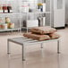 A stainless steel Regency dunnage rack with brown bags on it.