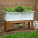 A white Mayne Fairfield planter box with plants in it.