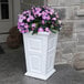 A white rectangular planter with a green plant in it.