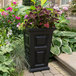 A Mayne black planter with a potted plant on an outdoor patio table.