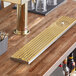 A Regency PVD gold surface-mount beer drip tray with rinser on a bar counter.