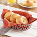 A basket of Original Bagel plain mini bagels on a table with orange juice.