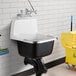 An American Standard white cast iron wall-mount utility sink with a mop and bucket.