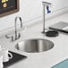 An American Standard stainless steel undermount sink with one compartment on a counter with white mugs.