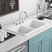 A white American Standard Quince sink with silver faucets over a metal surface.