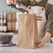 A person pouring coffee beans into a brown paper bag.