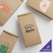 A variety of brown paper coffee bags with different designs and green and white text.
