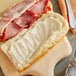 A sandwich with ham and cheese on a wooden board with a jar of Kraft Olive Oil Mayonnaise.