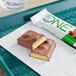 A ONE Chocolate Almond Bliss protein bar on a napkin next to a drink.