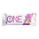 A ONE Fruity Cereal protein bar in white packaging with purple text and colorful donuts on the wrapper. The bar has pink and purple sprinkles.