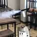 A person using a Goodway steam gun attachment on a table with a black pipe and chair.