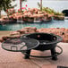 A round black Old Country BBQ Pits fire pit with a grill over the top.